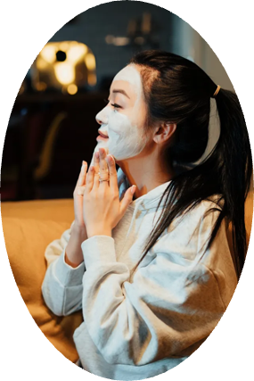 A woman with a white mask on her face is sitting on a couch.