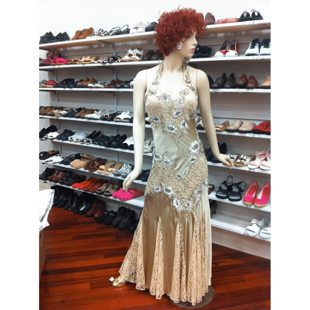 A mannequin wearing a long dress is standing in front of shelves of shoes.