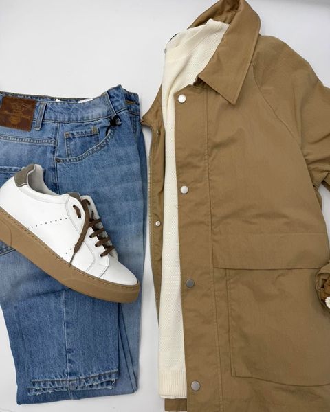 Jeans blu, scarpe da ginnastica bianche e un cappotto color cammello: un outfit casual.
