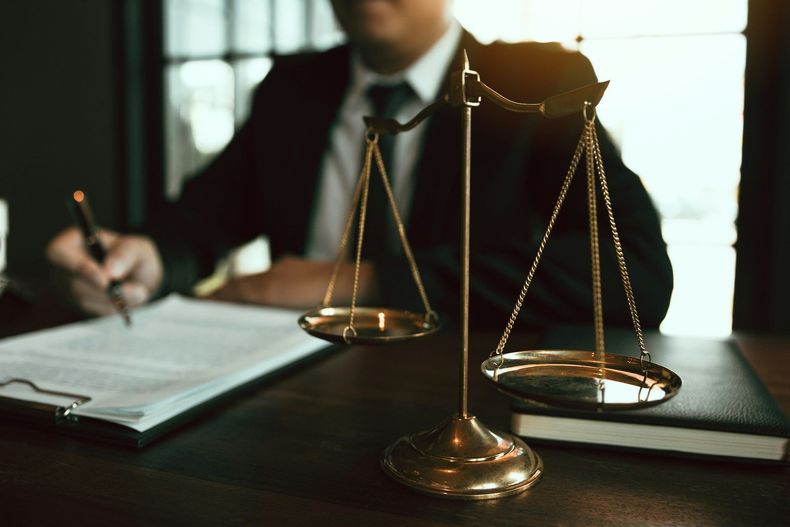 Lawyer at desk with brass scales of justice and open notebook in a dim office