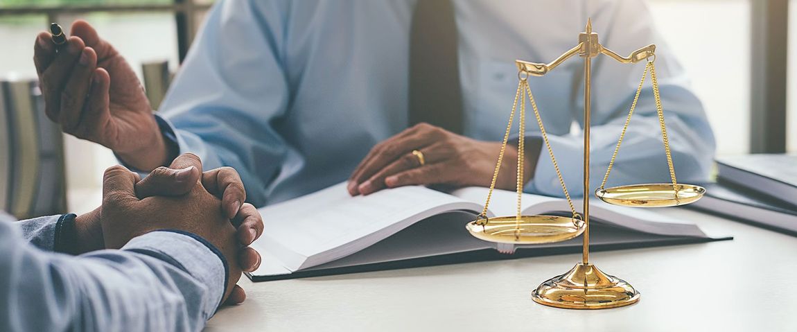 lawyer talking to client at the desk with justice scale