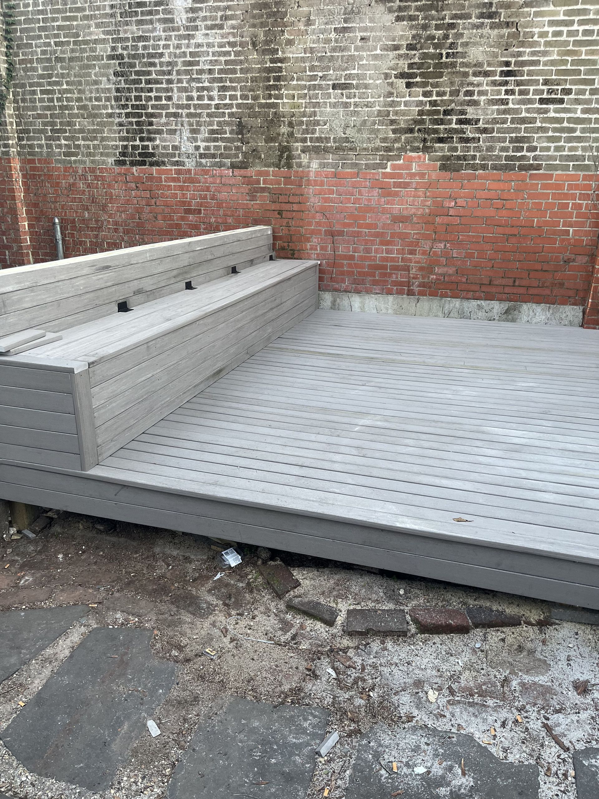 A wooden deck with a brick wall in the background.
