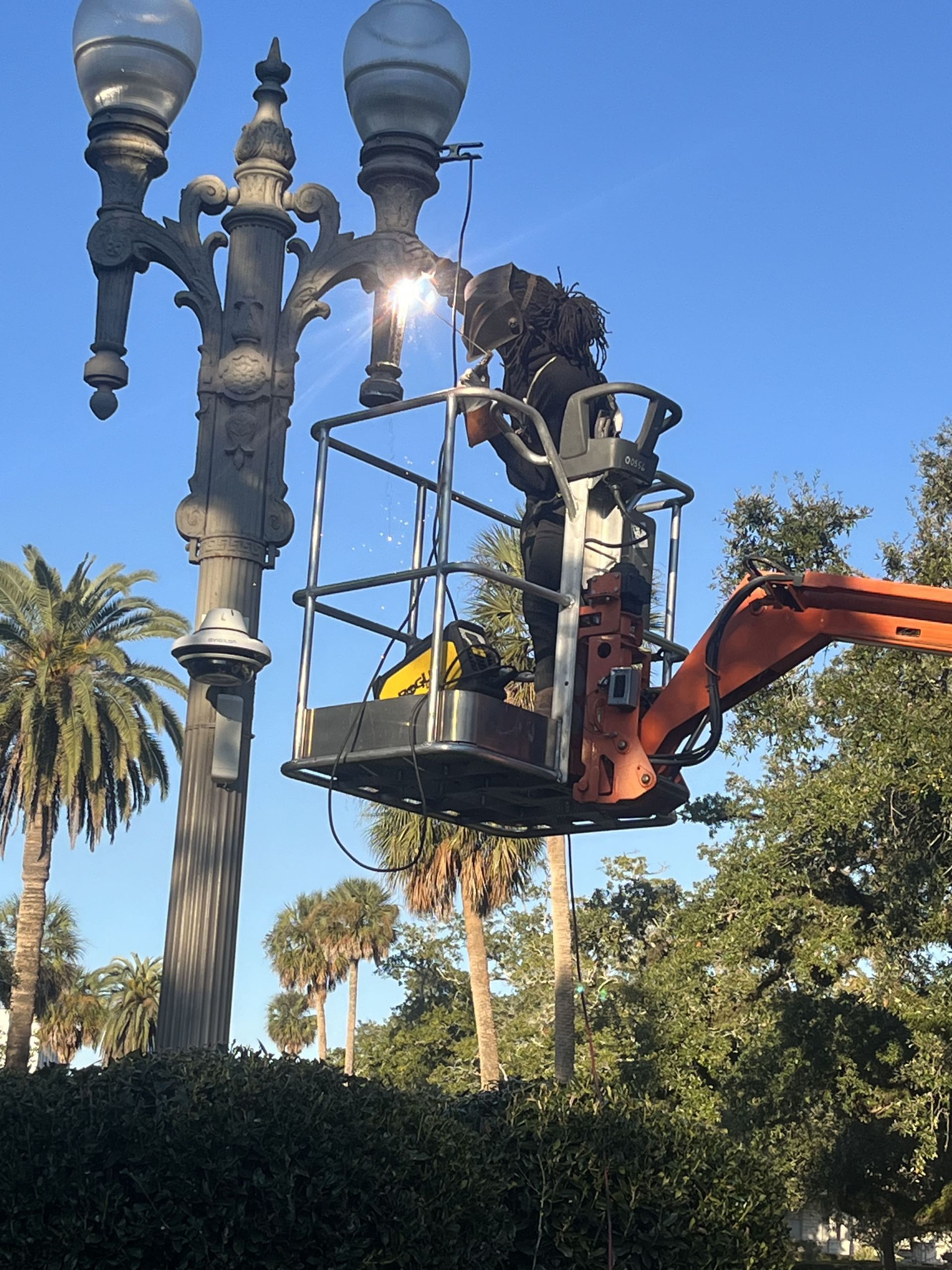 A man in a bucket is working on a street light