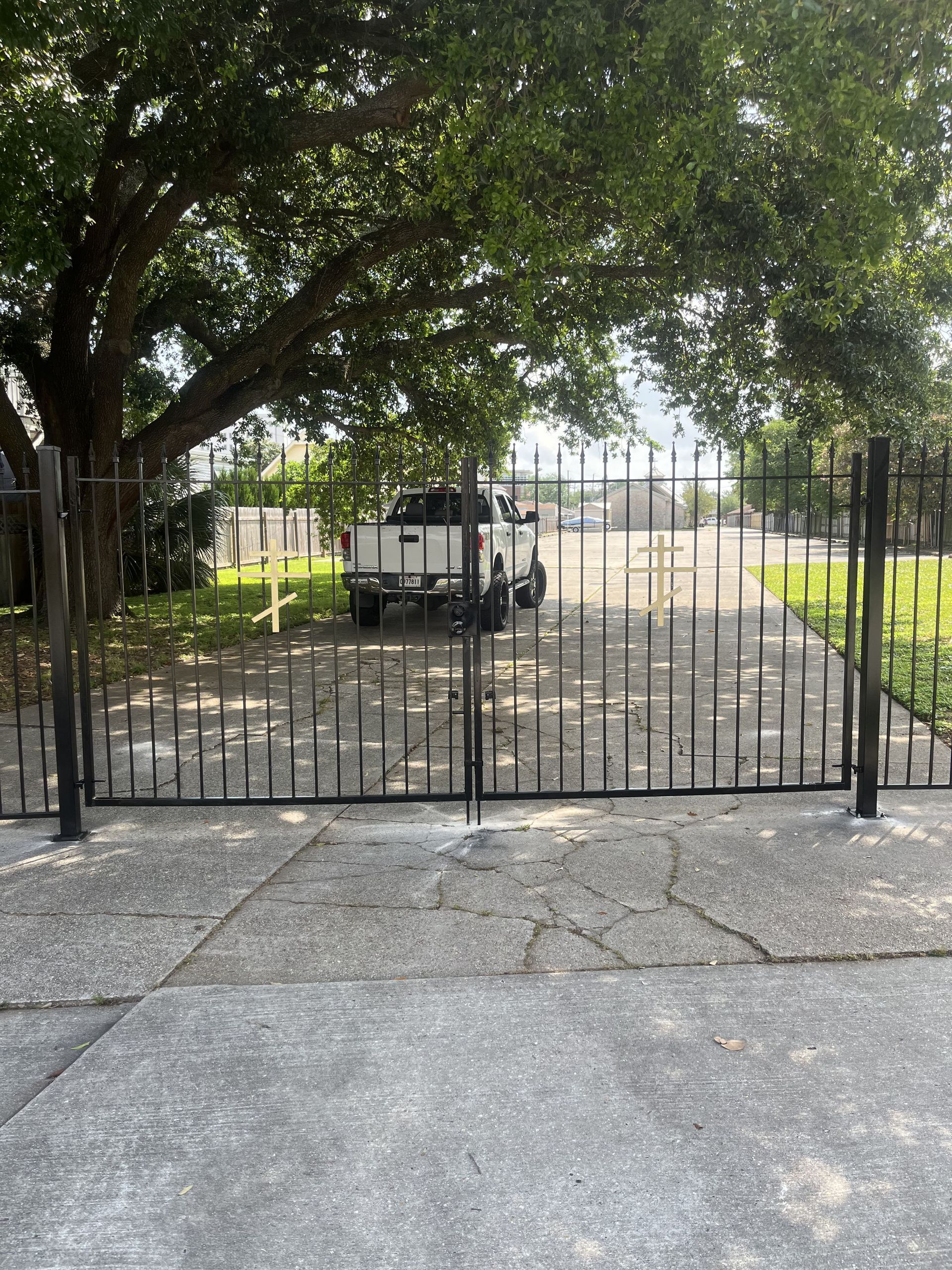 A white truck is parked behind a wrought iron gate