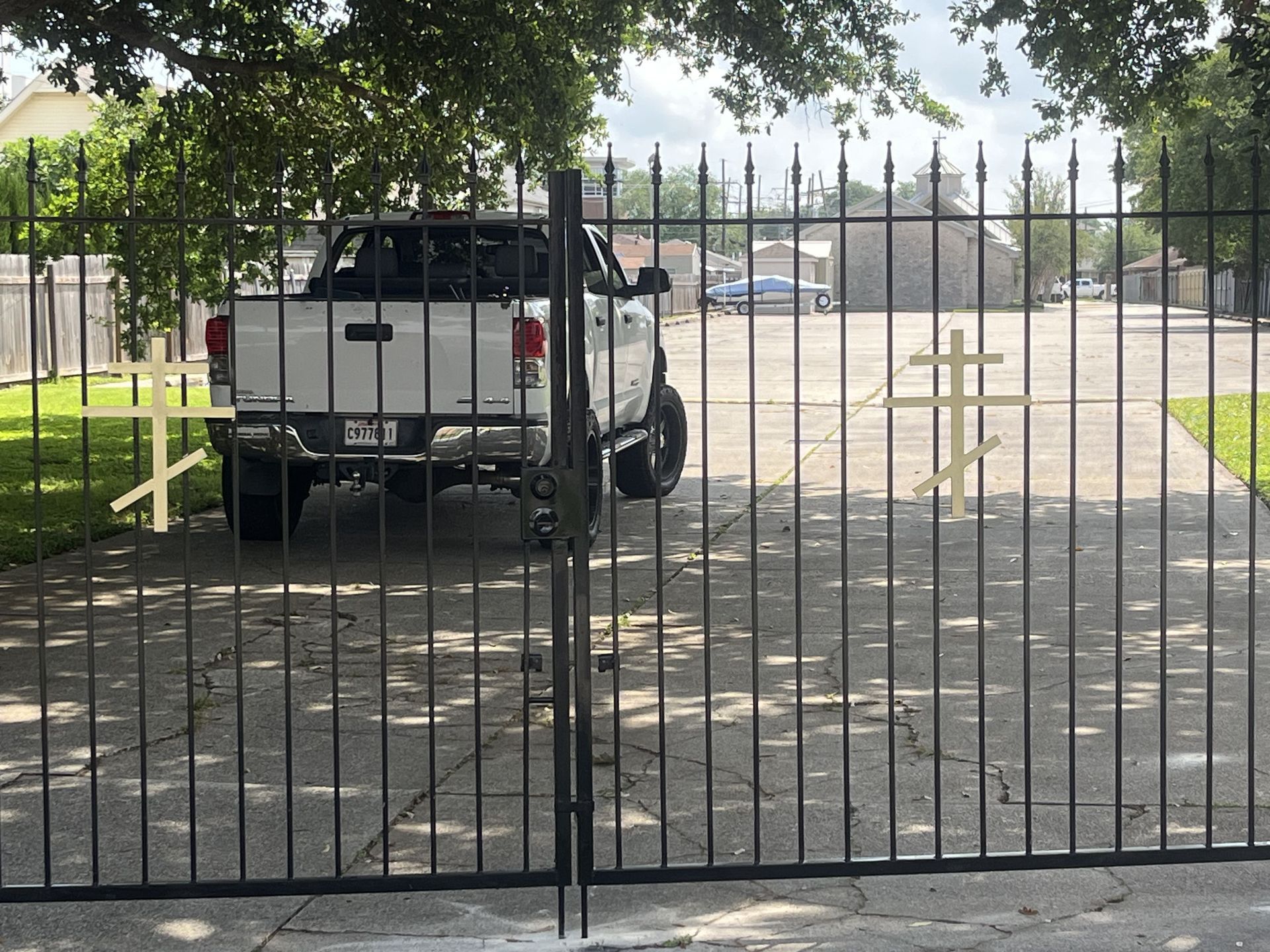 A white truck is parked behind a wrought iron gate