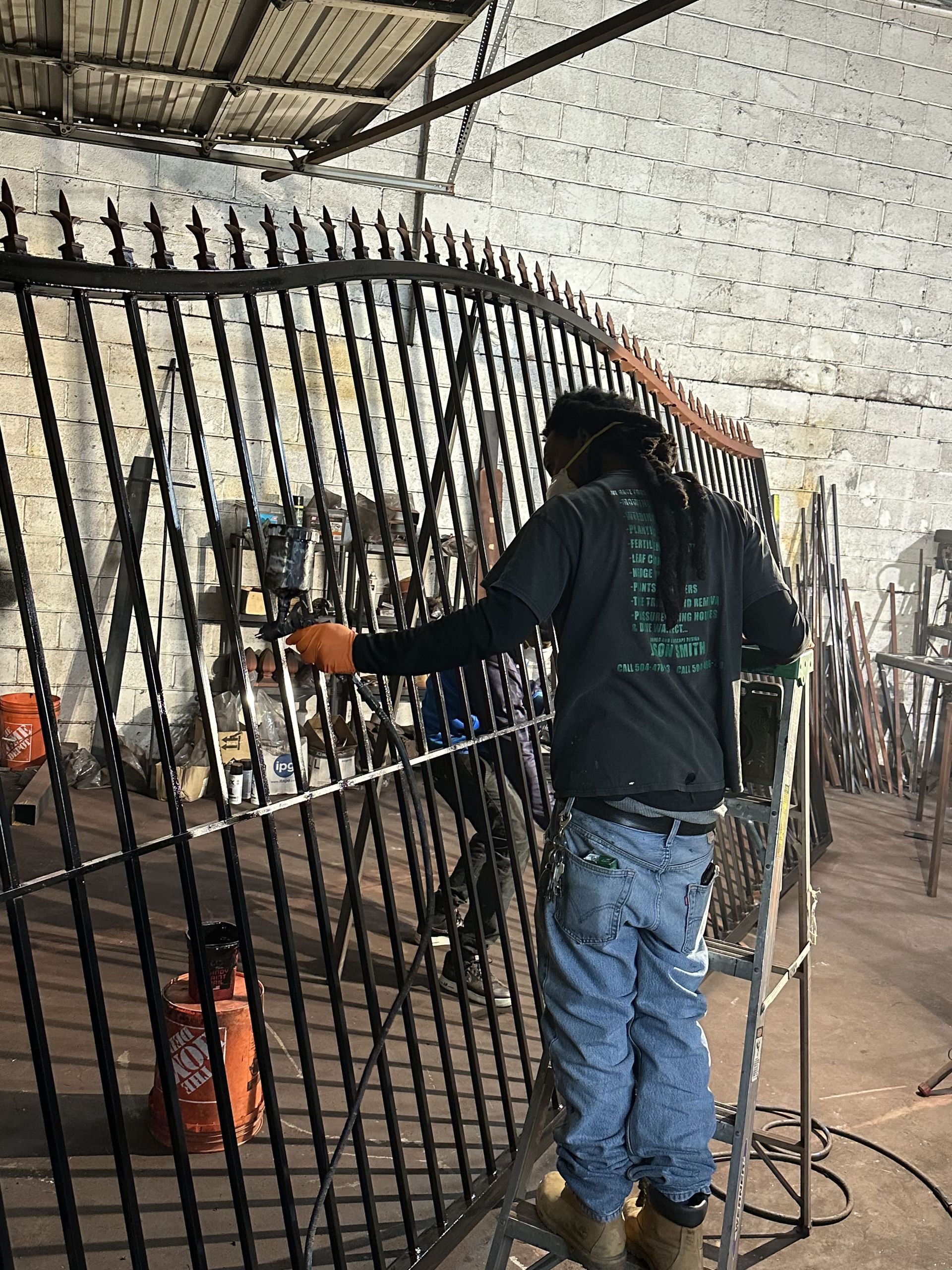 A man is welding a metal fence in a factory.