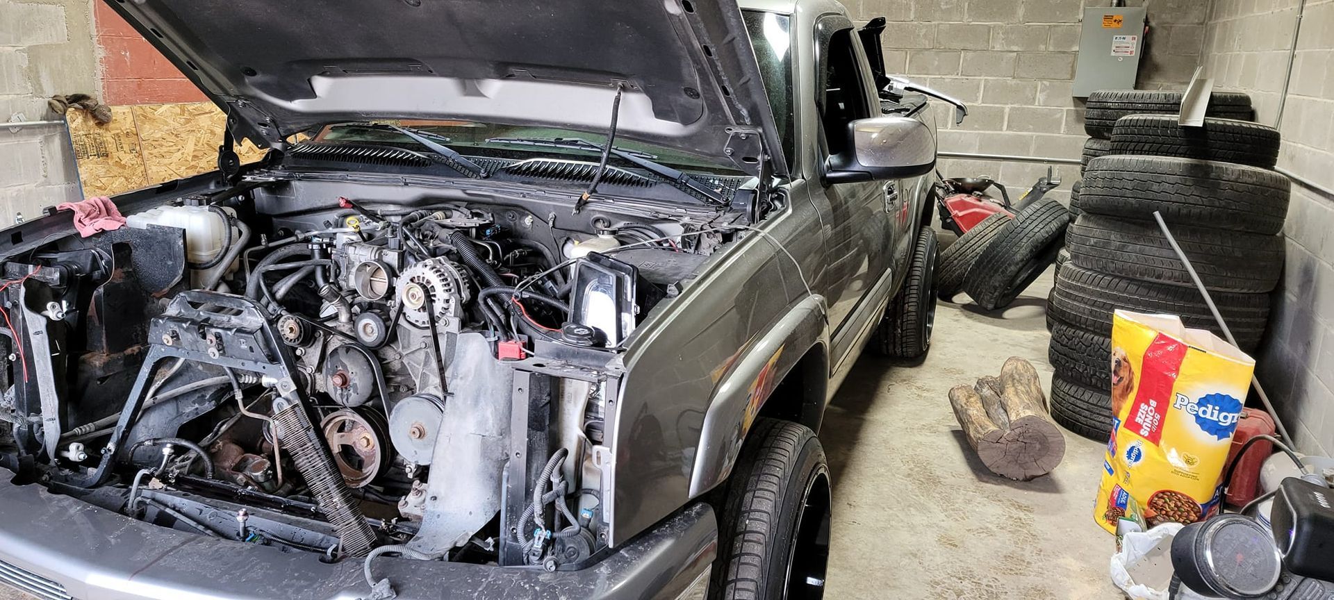 A truck with the hood up is sitting in a garage.