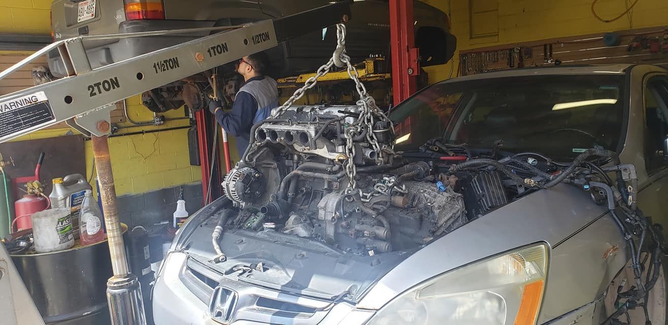 A car is being repaired in a garage with the engine removed.