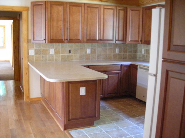 Kitchen with wood cabinets, light countertops, and tile backsplash.