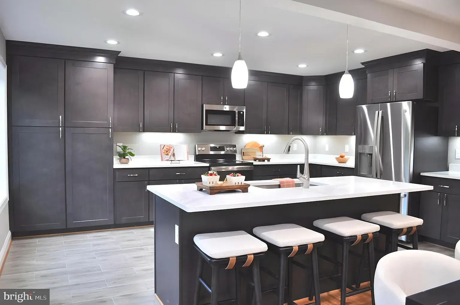 Dark gray modern kitchen with a large island, stainless steel appliances, and white countertops.