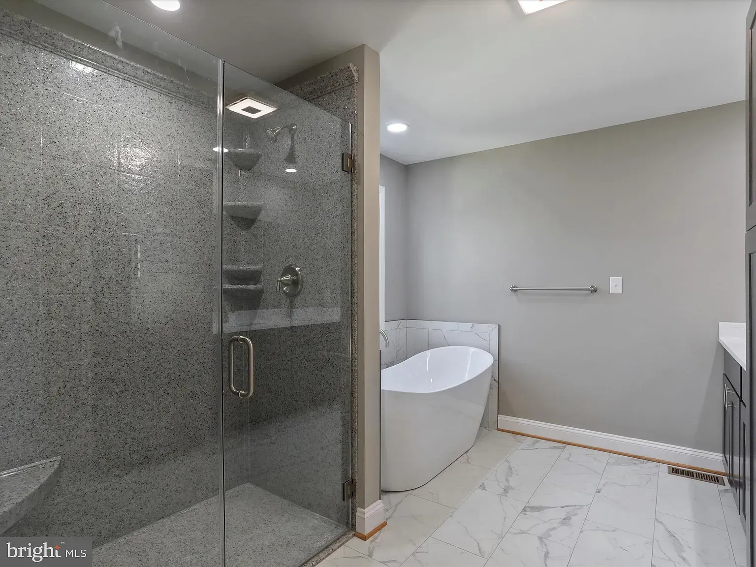 Modern bathroom with a glass shower, soaking tub, and gray walls.