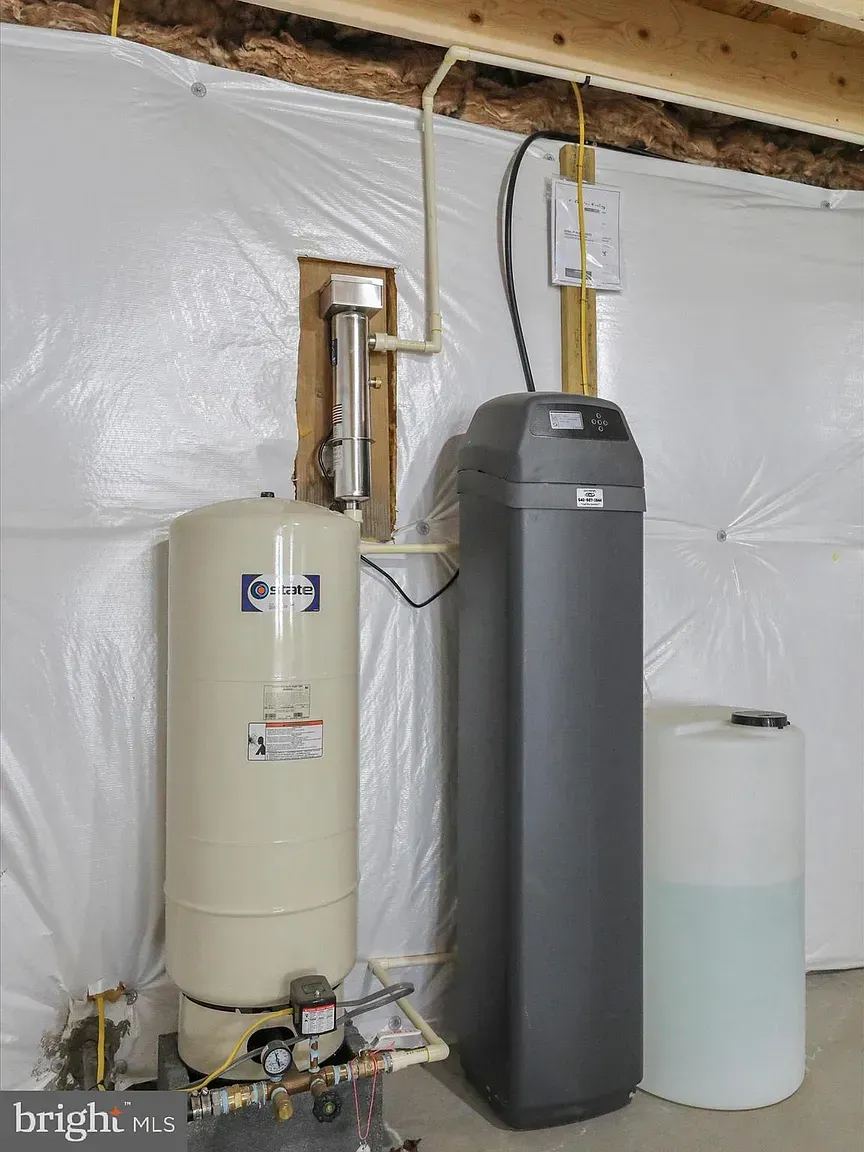 Water filtration and treatment system in a basement setting. Includes a pressure tank, softener, and brine tank.