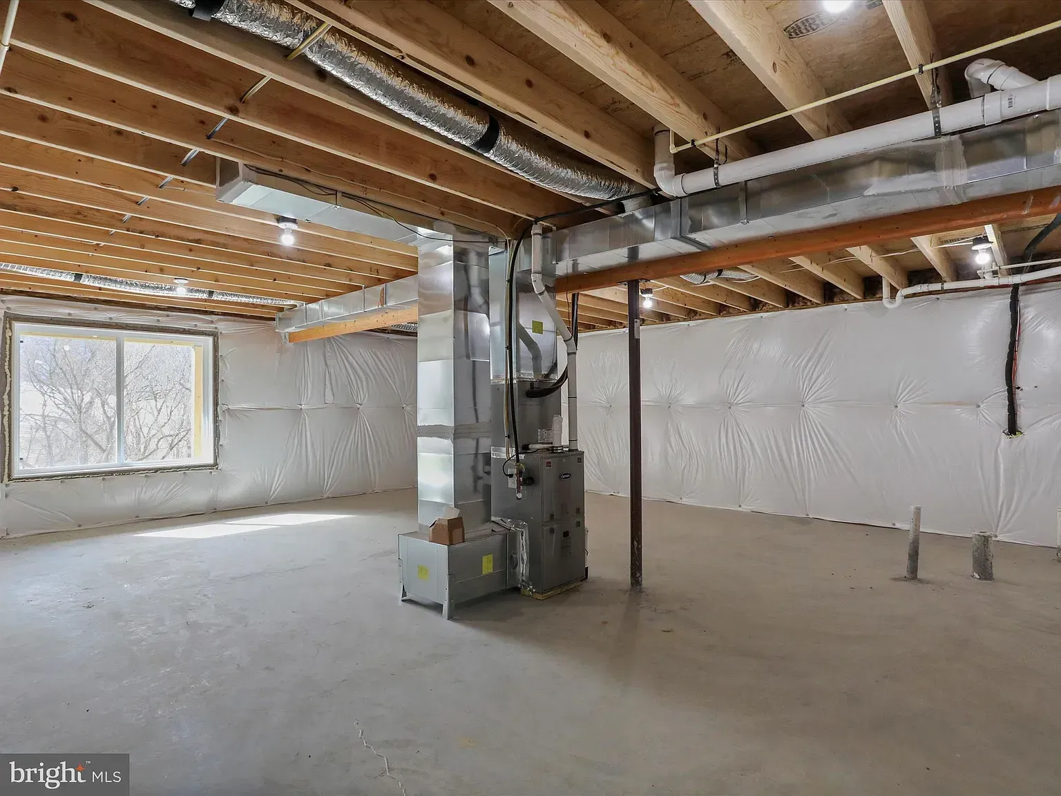Basement with concrete floor, insulation on the walls, and HVAC system.