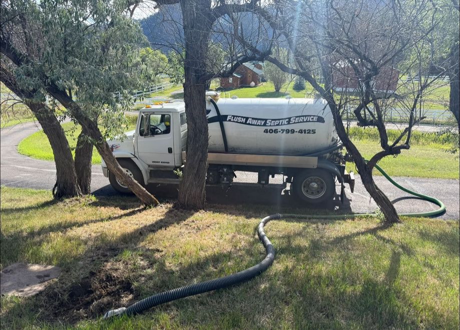 White utility truck with hose on grass under trees in a yard