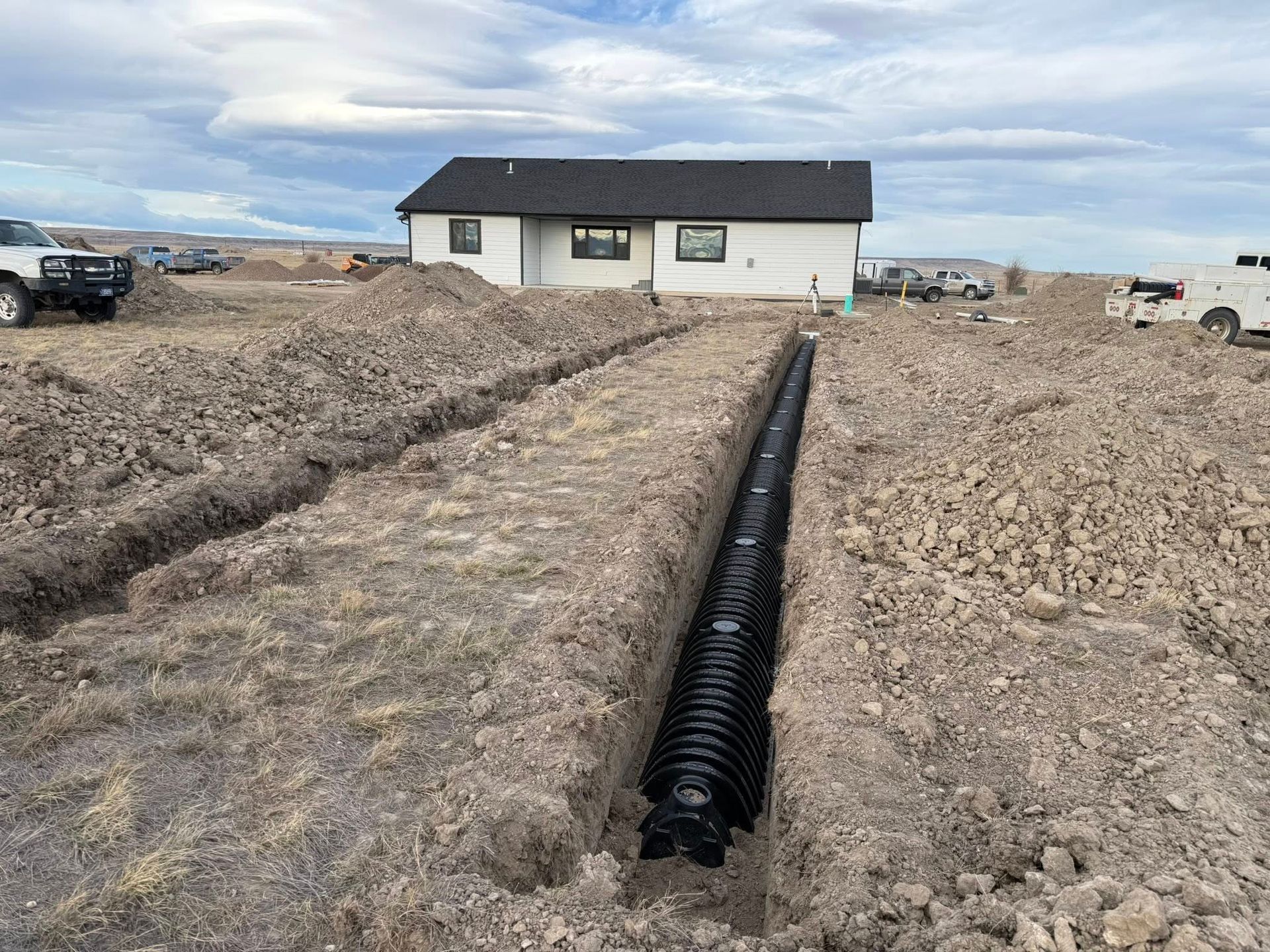 New house under construction with a long black drainage pipe in the dirt yard