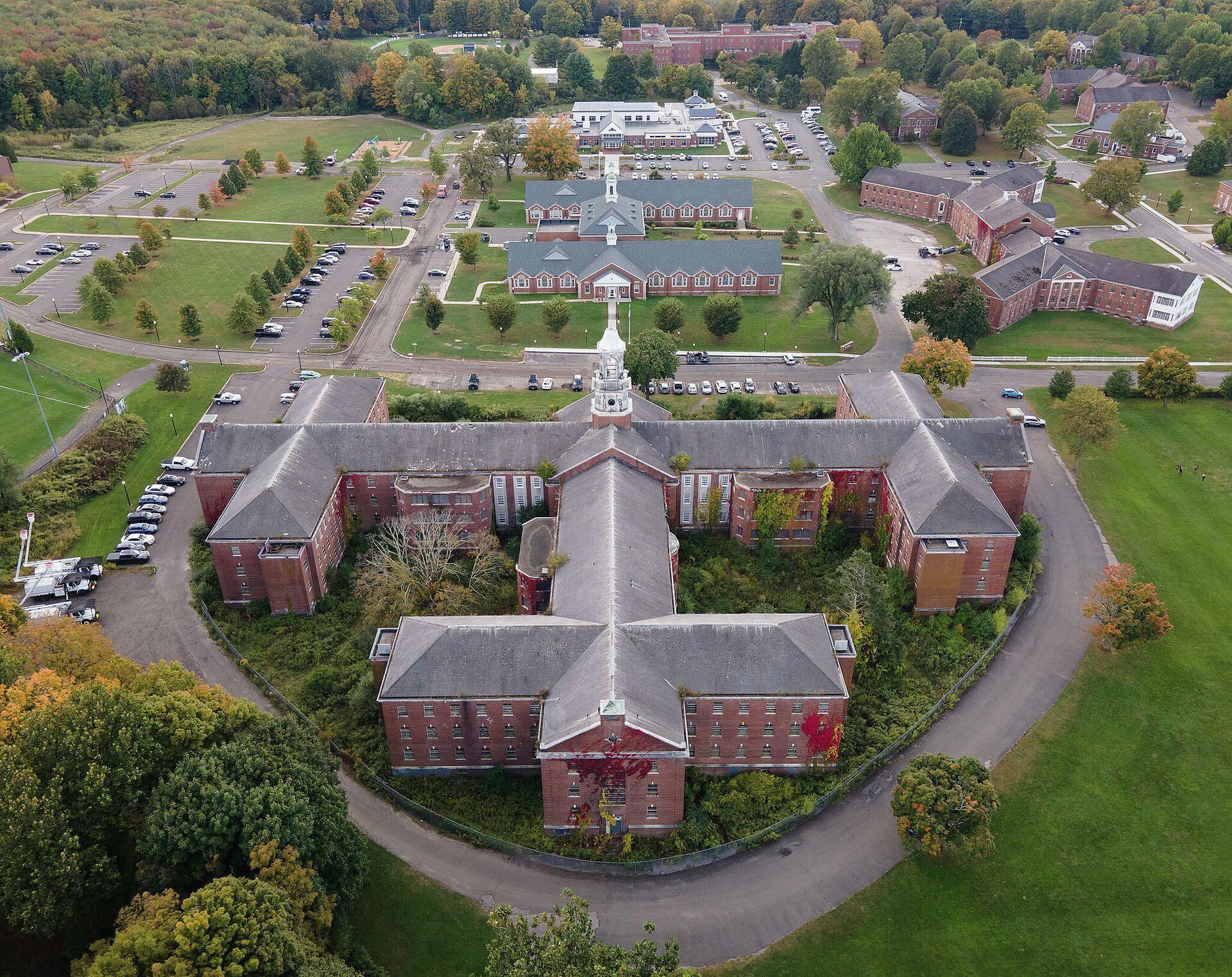 Aerial view of a red-brick residential campus with curved roads and trees.