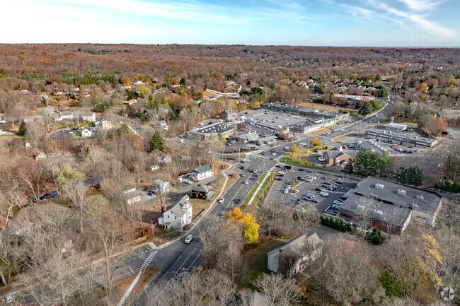 Aerial view of a suburban neighborhood with roads, houses, parking lots, and autumn trees