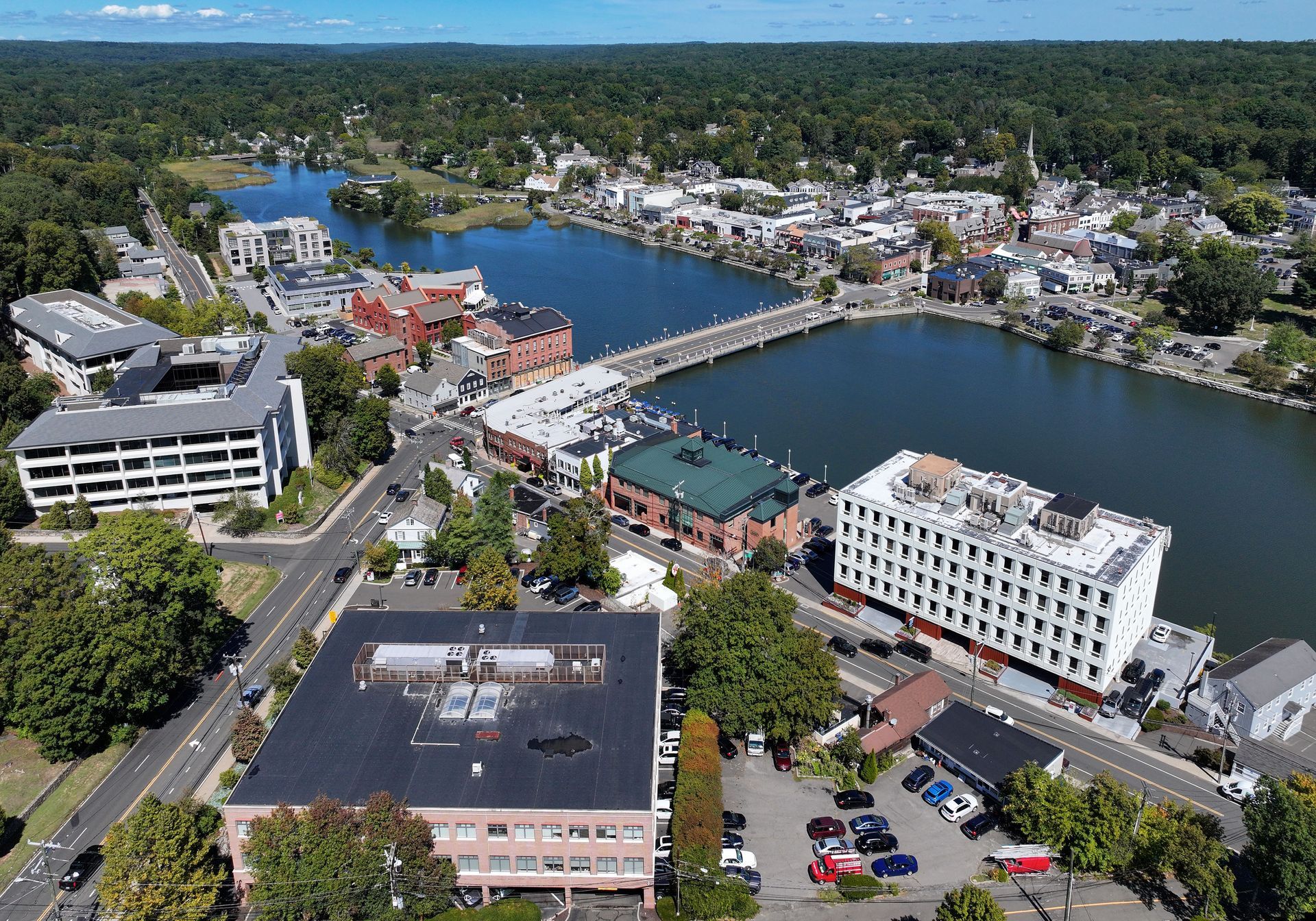 Aerial view of a waterfront town with a harbor, bridge, and white buildings along a river.
