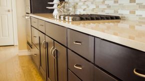 Modern kitchen with dark wood cabinets, light countertop, and tiled backsplash. Modern kitchen with dark wood cabinets, light countertop, and tiled backsplash.