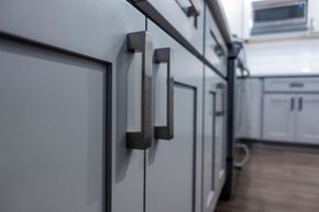 Gray kitchen cabinets with modern metal handles in a bright interior.