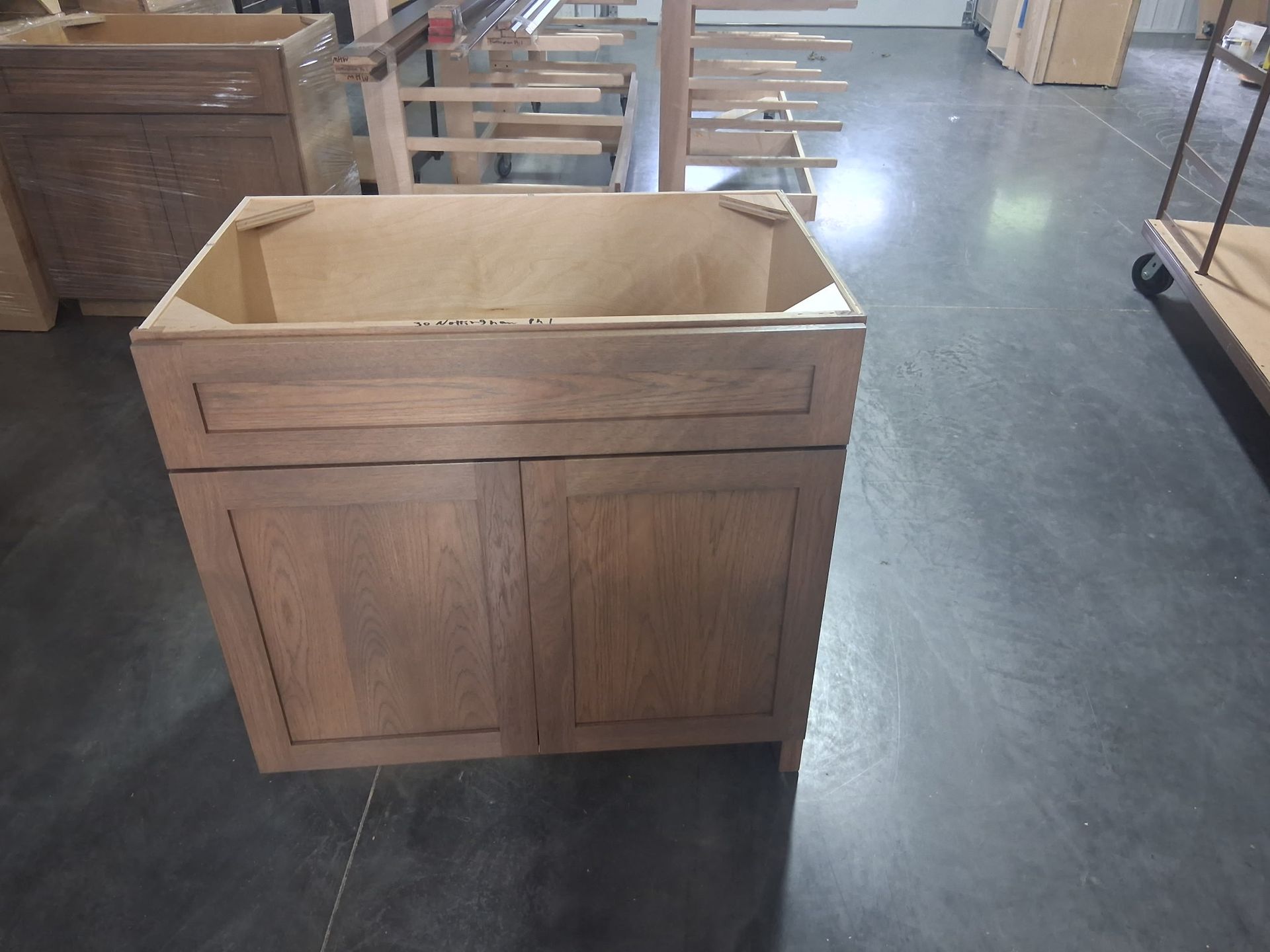 Empty wooden cabinet in a workshop, with an open top and panel doors.