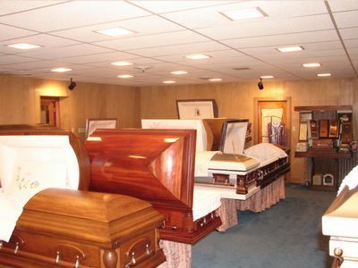 Funeral parlor showroom with several polished caskets displayed under warm ceiling lights