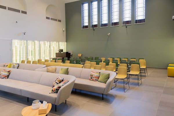 Lichte lounge met beige banken, gele stoelen en grote ramen in een moderne kamer.