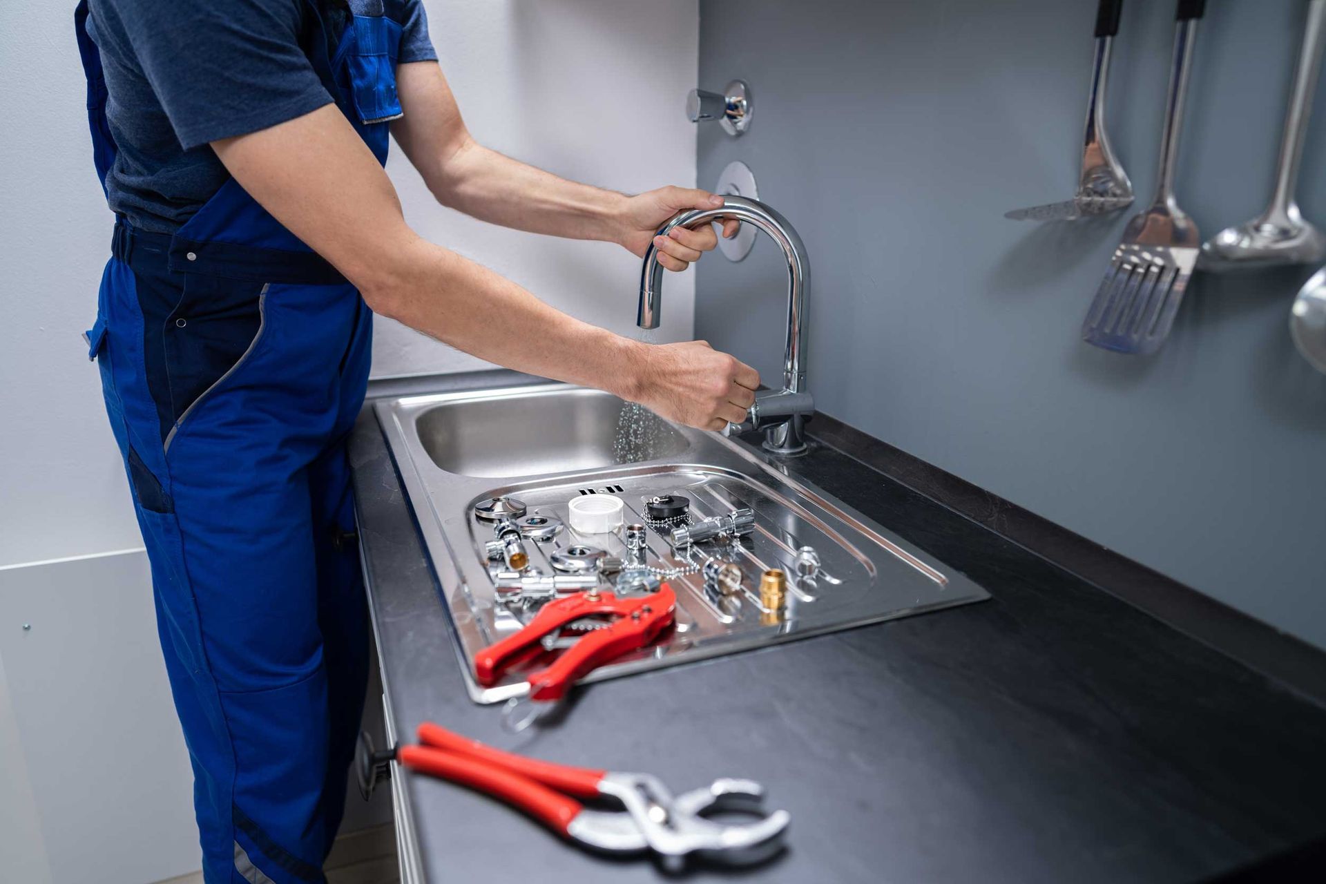 A plumber testing a kitchen faucet after completing repairs. A plumber testing a kitchen faucet after completing repairs.