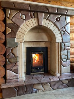 Stone fireplace with a lit fire, arched beige brick surround, and decorative stonework mantel