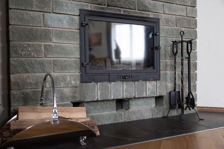 Modern fireplace with gray stone wall, black mantel, wall-mounted TV, and a sink on the left