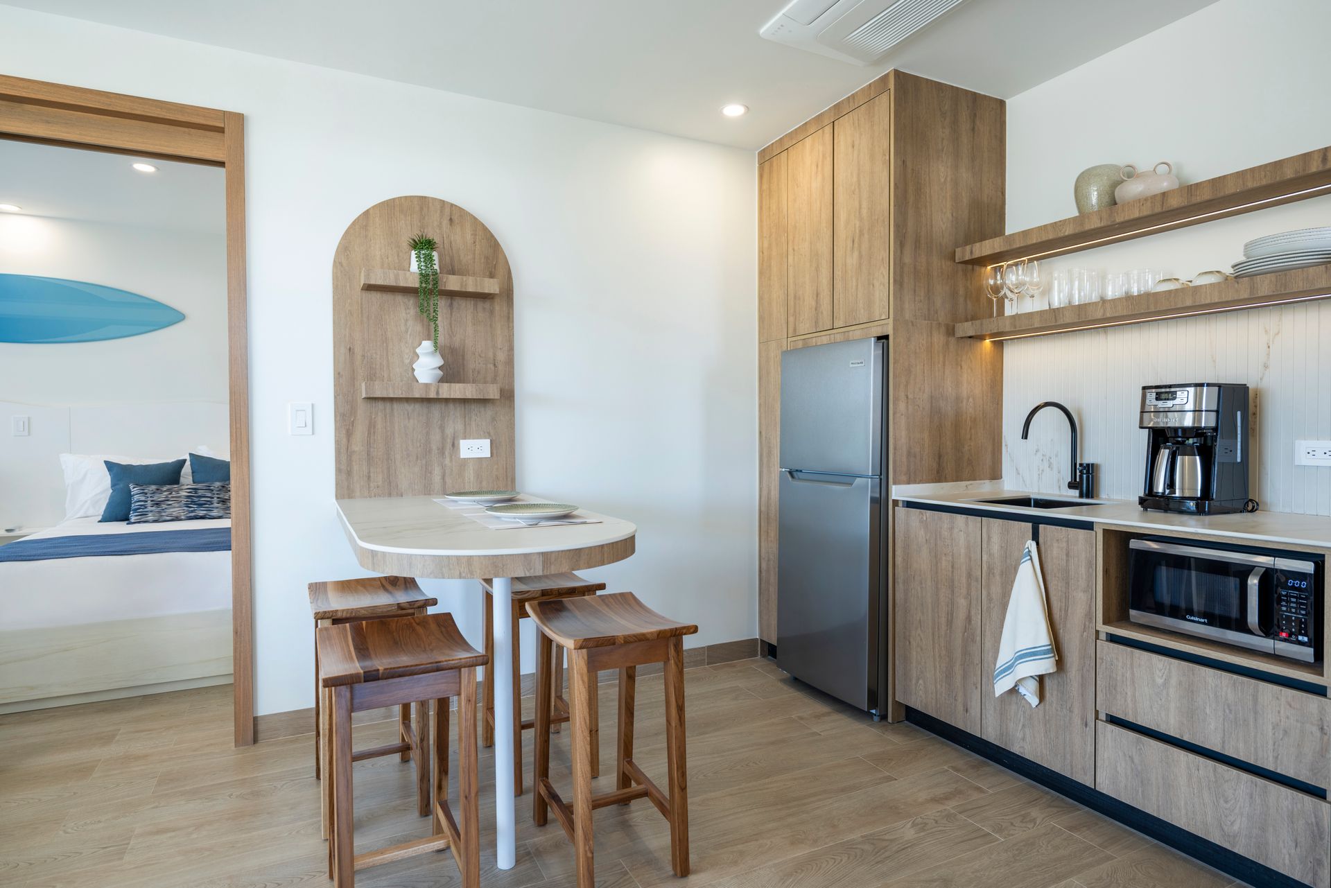 Modern kitchen with wooden cabinets, island table, bar stools, and stainless steel appliances
