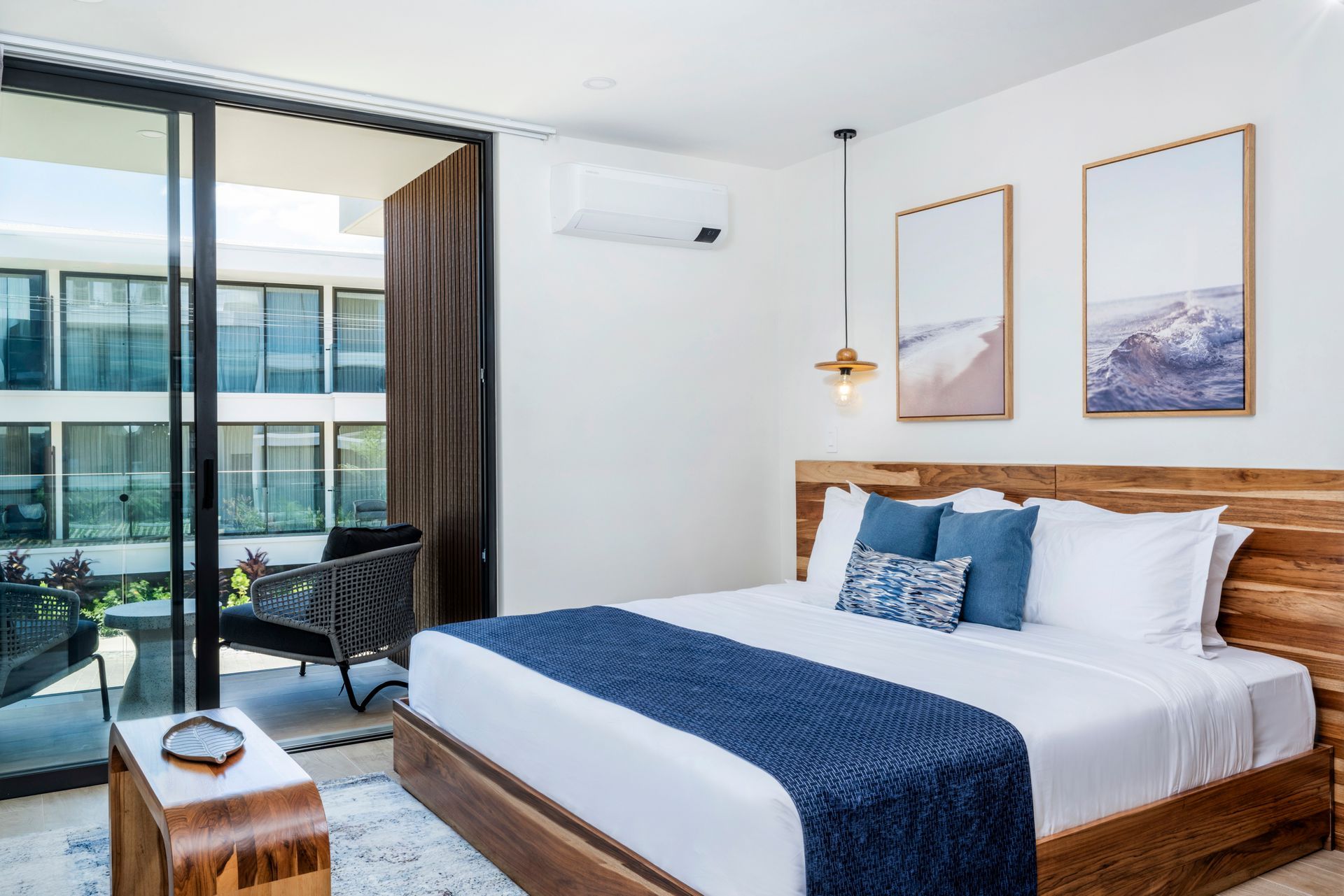 Modern bedroom with king bed, blue accents, and balcony view through large glass doors
