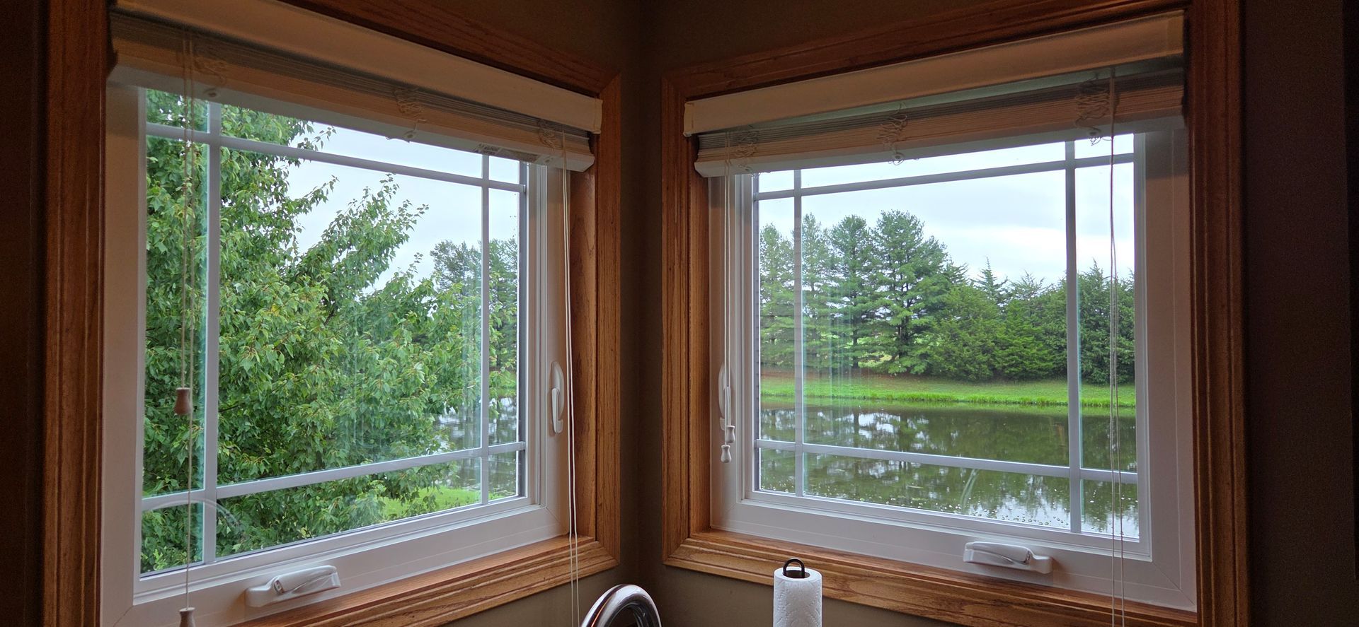 Wooden window seats overlooking a green pond and trees outside