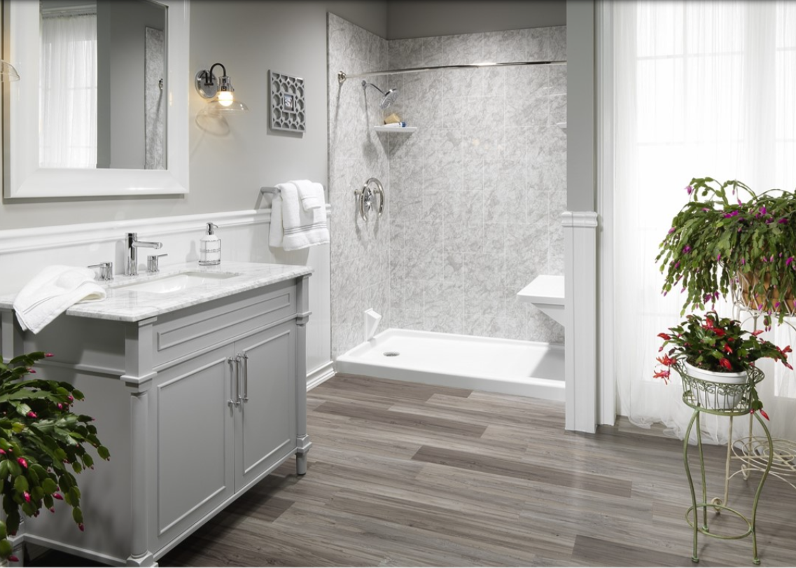 Bathroom with gray vanity, shower, and wood-look flooring. Fern and red flowers in a pot.