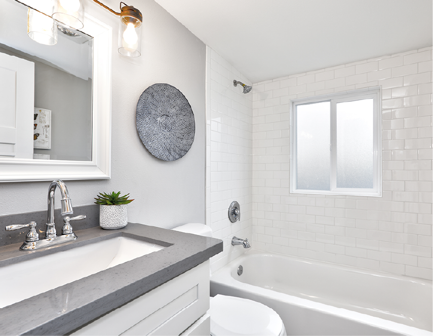 Bathroom with white subway tile, gray vanity, and round wall art.