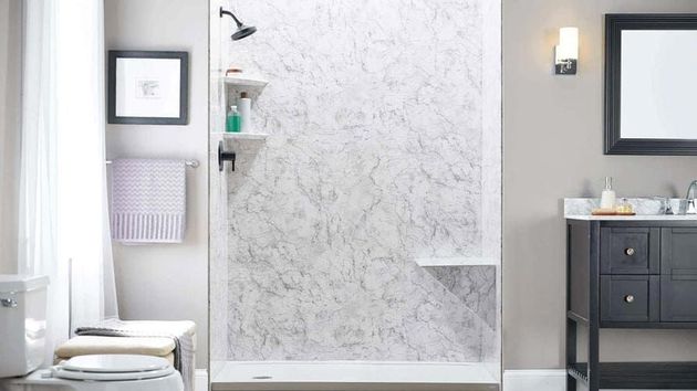 Bathroom with a marble-patterned shower, storage shelves, and a built-in seat. A framed picture and towel rack are to the left.