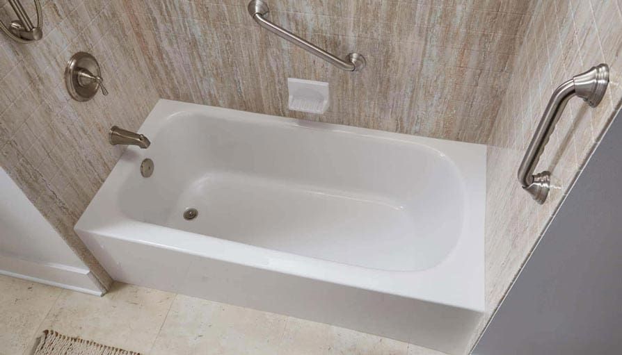 White bathtub in a shower enclosure with beige wall panels and safety grab bars.