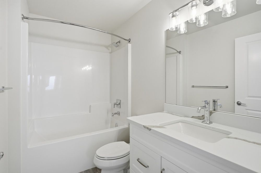 Bathroom with navy blue vanity, gold fixtures, and a white countertop. Doorway leads to a window.