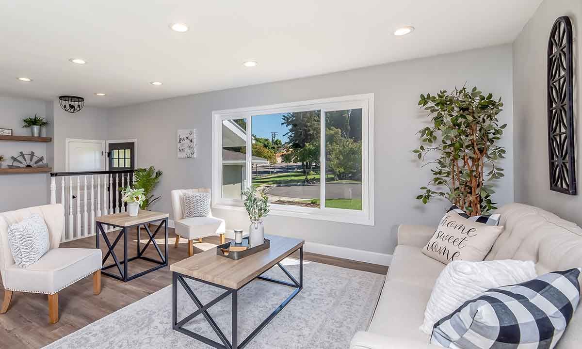 Living room with white sofa, chairs, and wooden coffee table, facing a large window with a view.