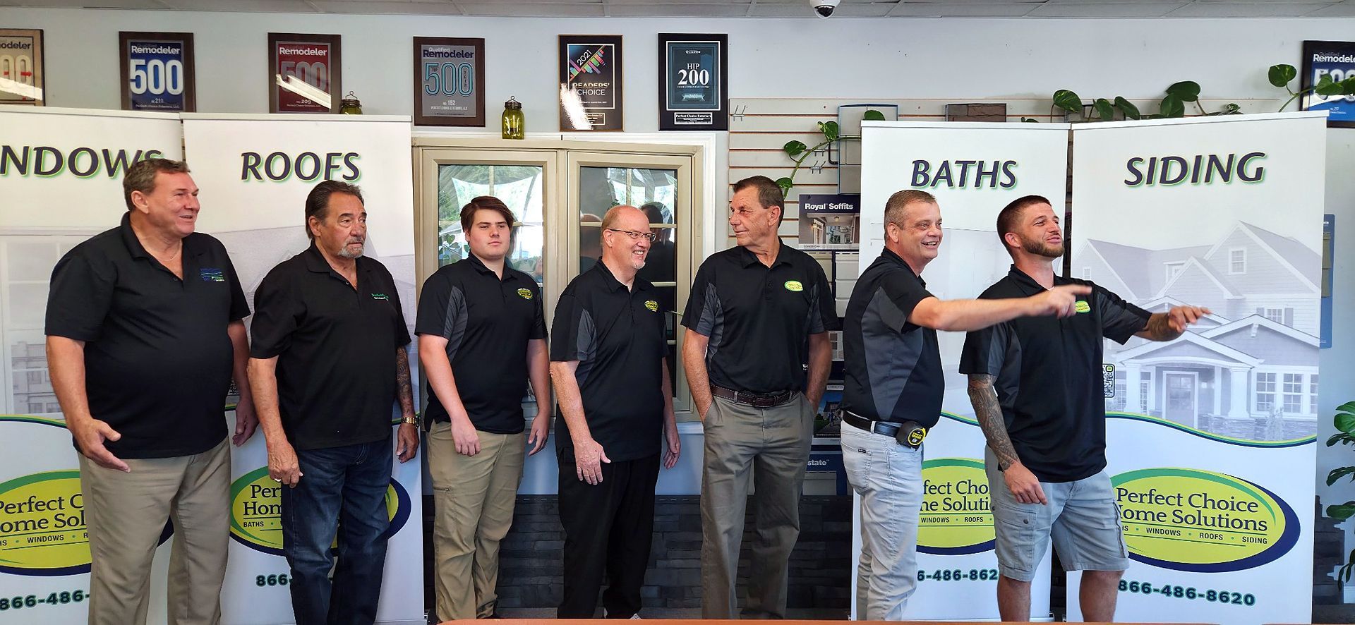 Group of people in black polo shirts stand in front of a sign