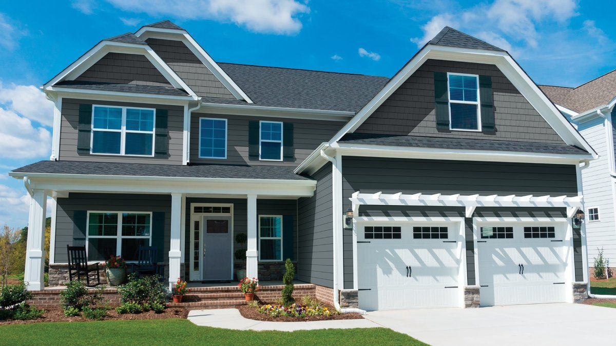 Suburban two-story gray house with white trim and a double garage under a blue sky