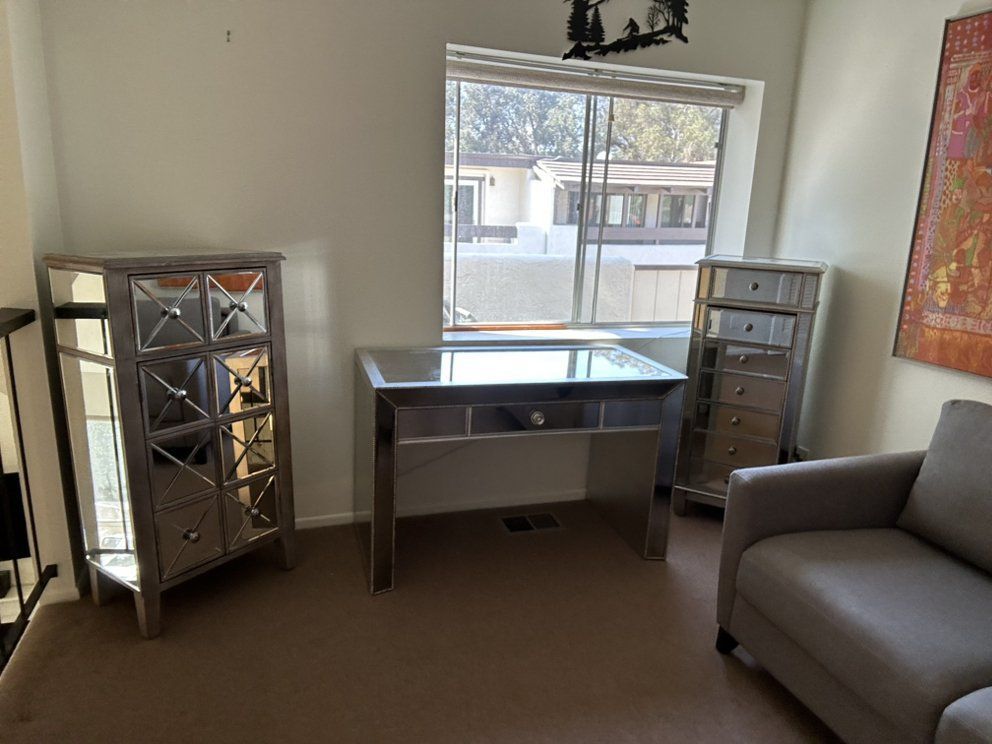 Mirrored furniture set in a room with a window. Includes a cabinet, desk, and chest of drawers.