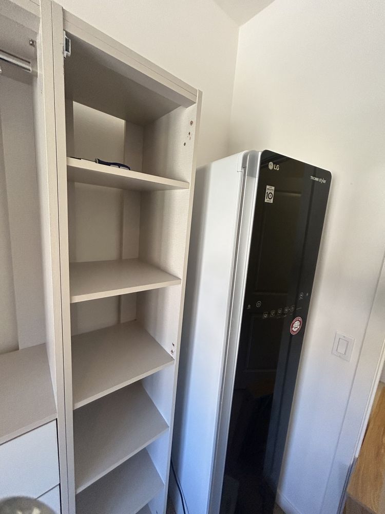 An open cabinet with shelves next to a black computer tower.