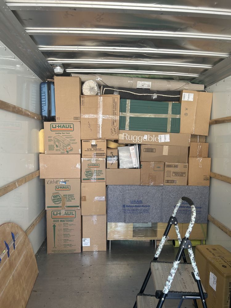 Boxes and furniture stacked inside a moving truck. A step ladder sits in front.