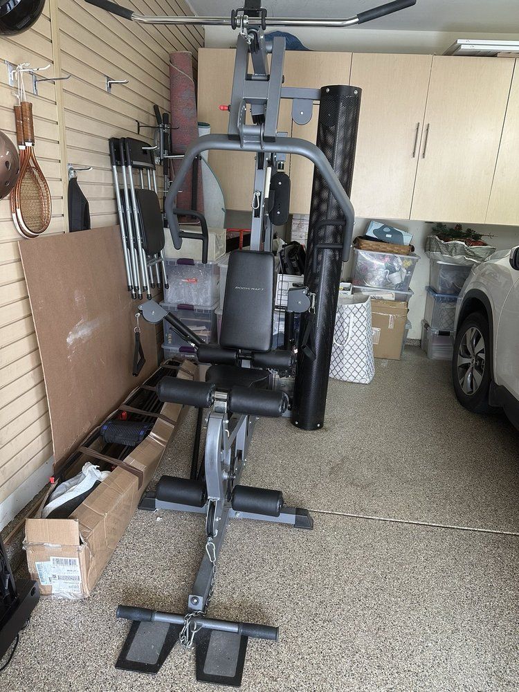 Weight machine in a garage. Gray and black, with multiple stations.