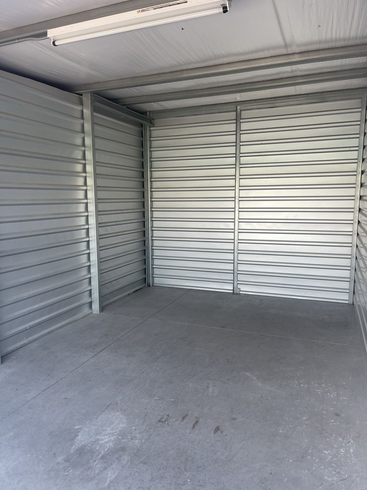 Empty storage unit with gray walls, floor, and a bright overhead light.
