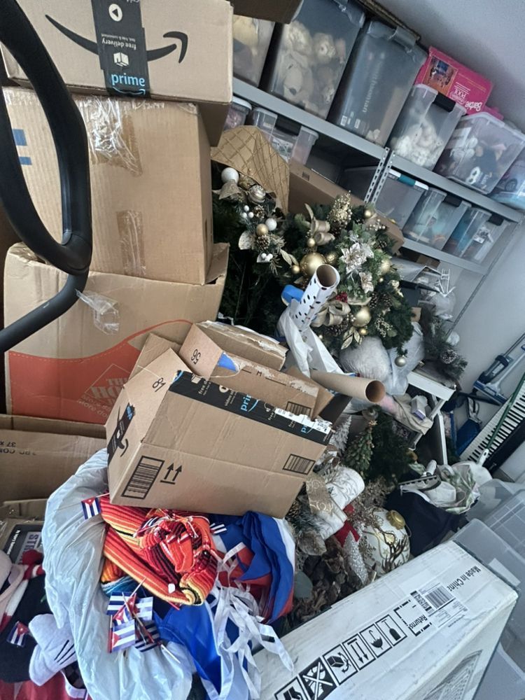 Boxes, Christmas decorations, and storage bins piled up in a cluttered room.