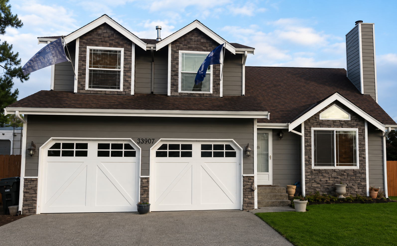 Suburban house with double white garage doors, stone accents, and Canadian flags by the entrance