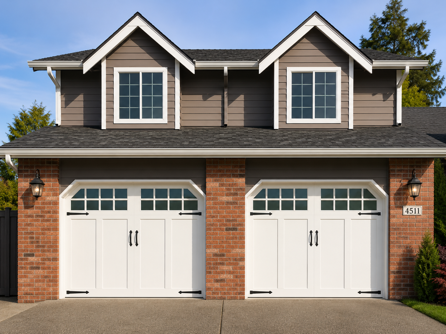 Two-car brick house with white garage doors and gray dormer windows under a blue sky