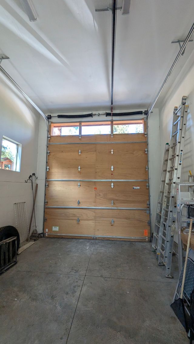 Two workers moving materials in a room with a scaffold and ladder under ceiling repair.